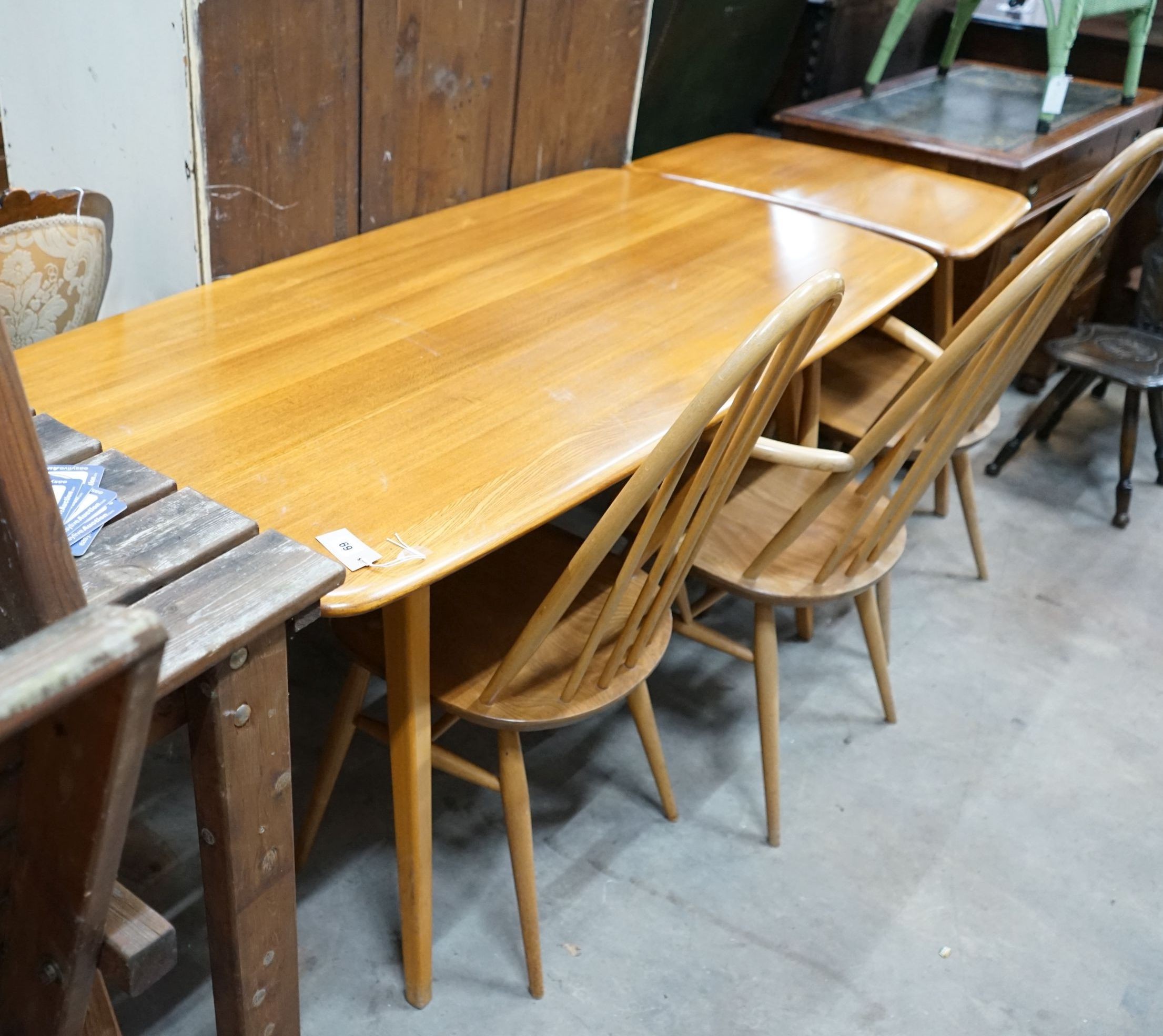 An Ercol rectangular light elm dining table with extension section, length 150cm, depth 76cm, height 72cm and three Ercol elm and beech comb back chairs, one with arms